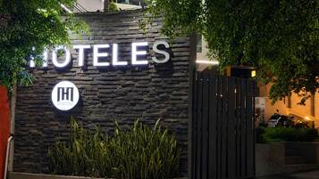 A hotel entrance with a stone facade, a prominent sign, and a gated driveway.
