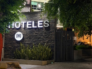 A hotel entrance with a stone facade, a prominent sign, and a gated driveway.