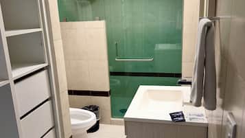 A bathroom with a toilet, a shower, and a sink.
