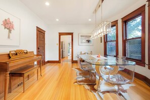 A modern kitchen with a glass dining table, wooden cabinets, and a view of the outdoors through large windows. - West Highlands House Walk to Shops & Dining (Denver)