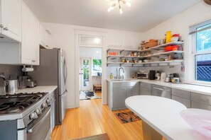 A modern kitchen with stainless steel appliances, white cabinetry, and a view of the outdoors. - West Highlands House Walk to Shops & Dining (Denver)