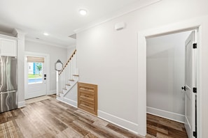 A modern kitchen with a stainless steel refrigerator, a wooden floor, and a white door leading to another room. - Wrightside Retreat - Newly built modern living (Wilmington)