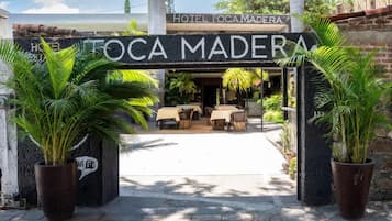 The entrance to Hotel Tocamadera with outdoor seating and potted plants.