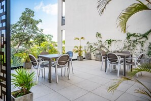 Eine Terrassengruppe mit Tisch und Stühlen, umgeben von Blumentöpfen und einer weißen Mauer.