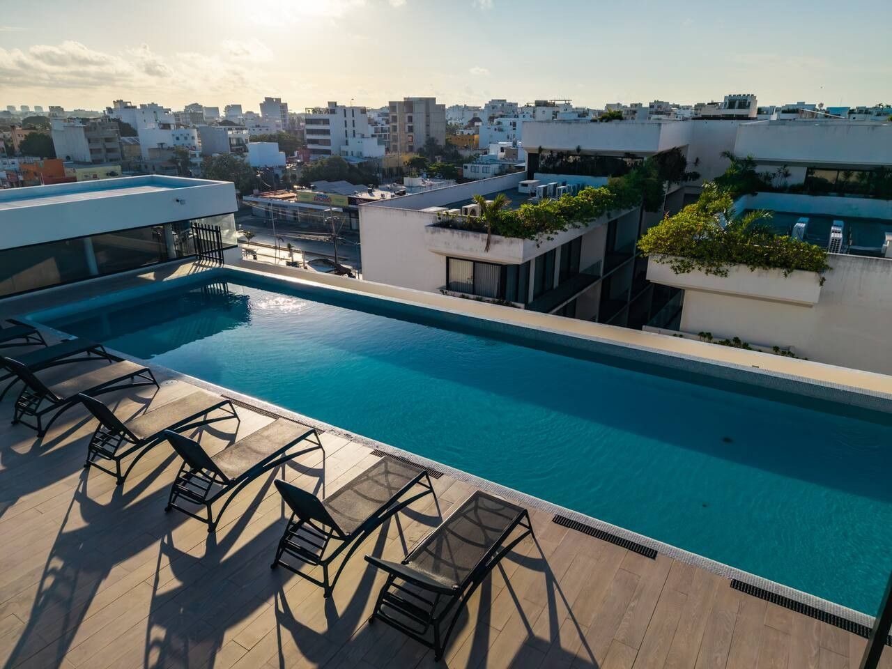 Ein Pool auf dem Dach mit Liegestühlen, umgeben von Gebäuden.