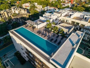 Une piscine sur le toit, dotée de chaises longues et offrant une vue sur les bâtiments environnants.