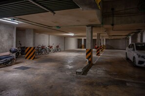 An underground parking garage with concrete pillars, a white car, and several bicycles parked. - 2 BR Penthouse | Private Pool & Parking | Sleeps 8 (Playa del Carmen)