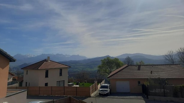 A residential area with houses, a parked car, and a mountain range in the background. - La Villa des Cimes (Pelleautier)