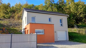 A two-story building with a garage, surrounded by a fence and trees.