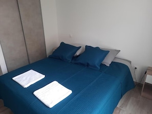 A bed with a blue bedspread, two pillows, and two folded white towels. - La Villa des Cimes (Pelleautier)