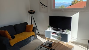 A modern living room with a sofa, a coffee table, a TV on a white stand, and a floor lamp.