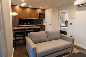 Un espacio habitable compacto con kitchenette, un sofá y un comedor.