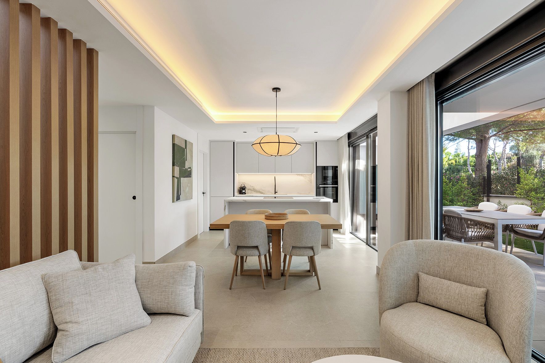A modern interior with a dining area, kitchen, and a view of the outdoors.
