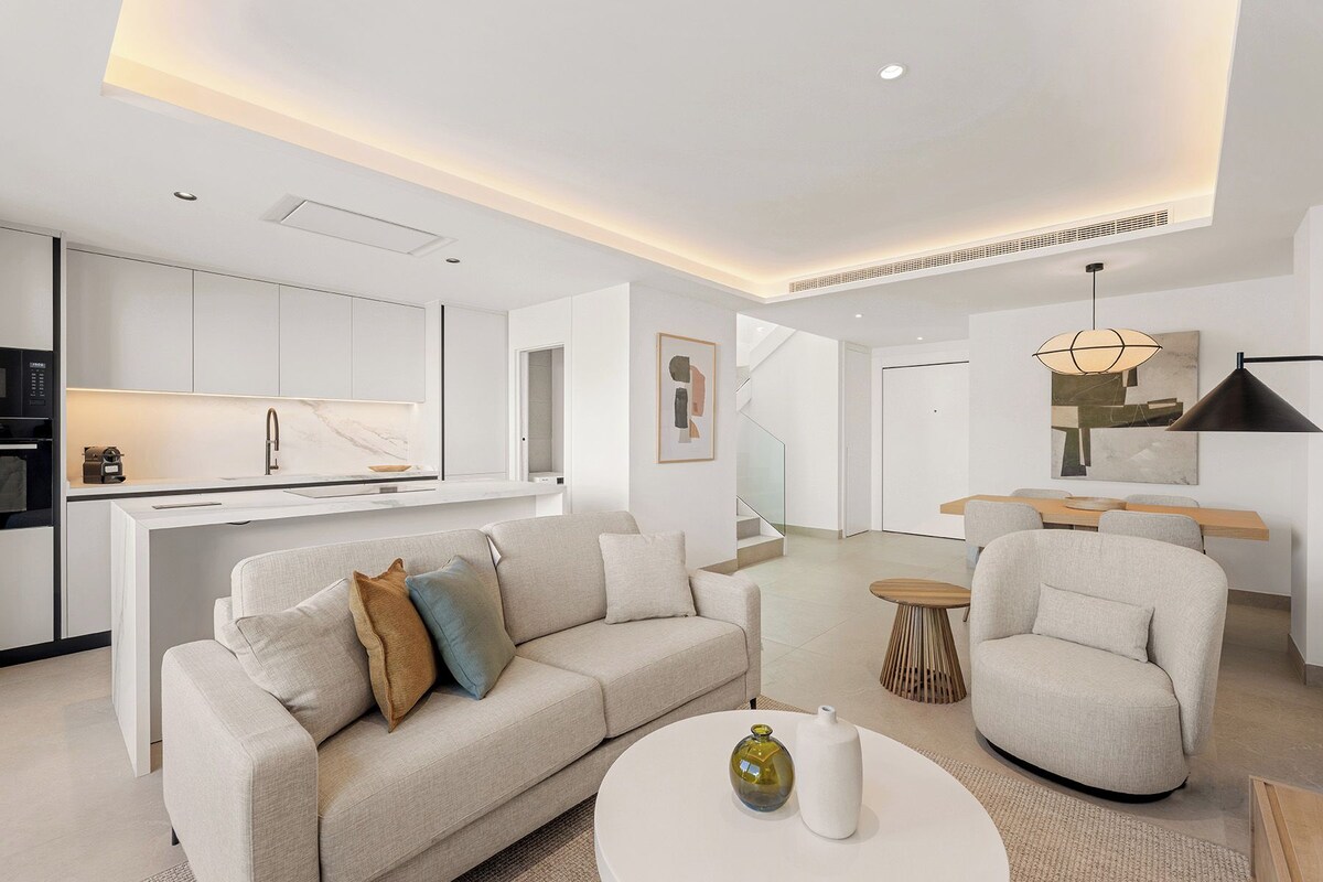 A modern living room with a sofa, armchairs, and a coffee table.