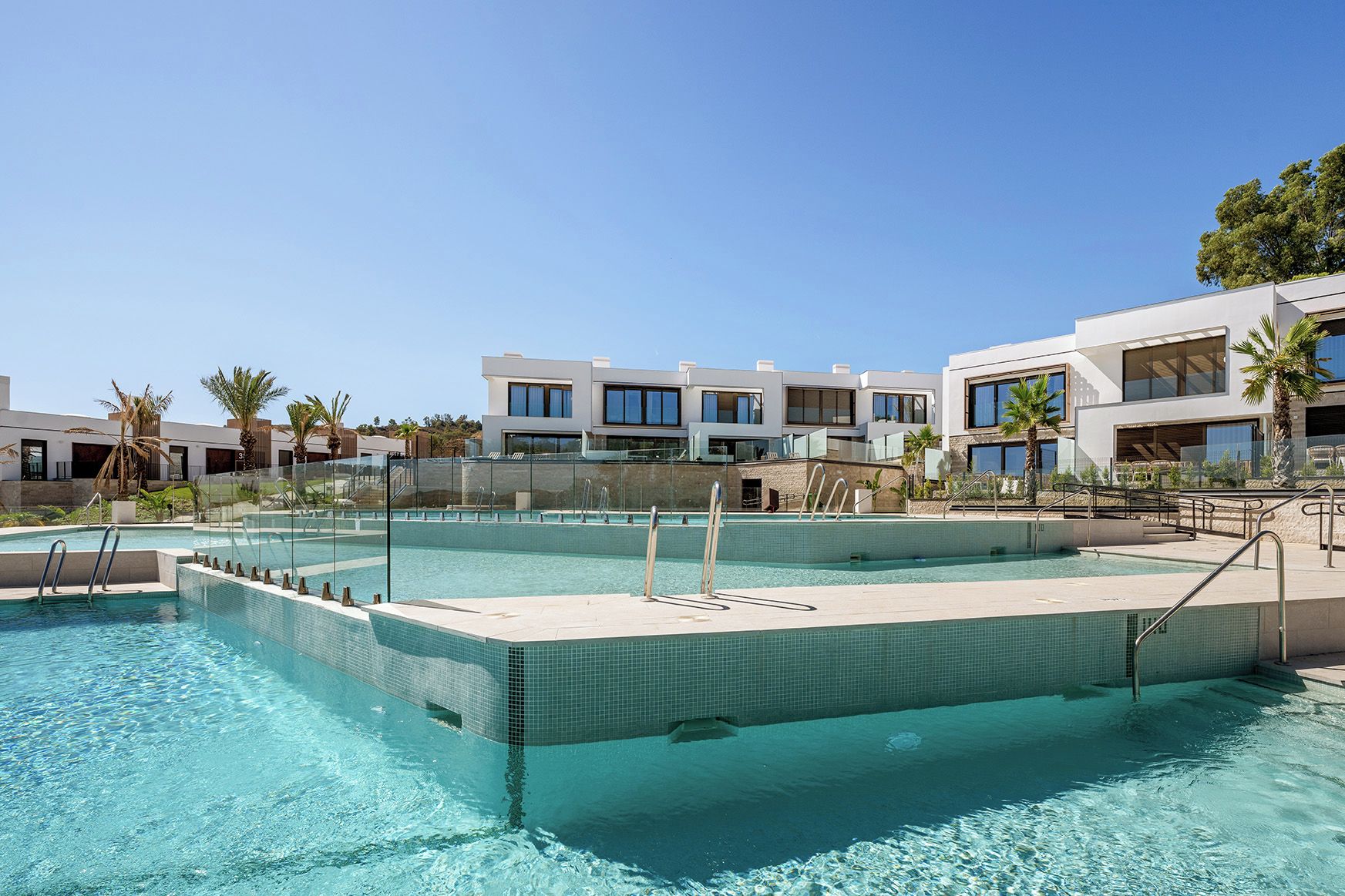 Una piscina con agua azul cristalina, rodeada de edificios modernos con balcones.