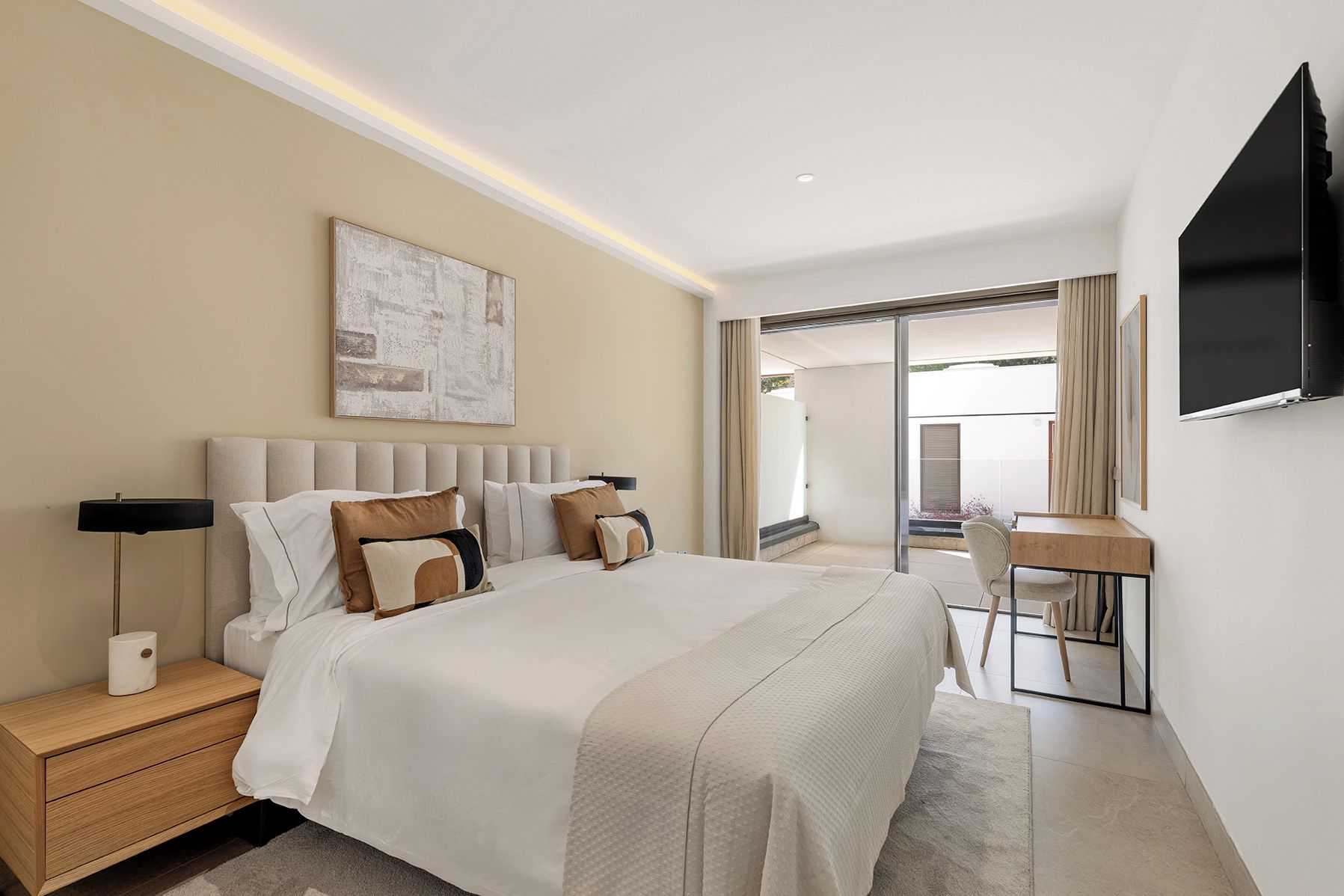 Una habitación de hotel con cama, mesitas de noche, escritorio y televisor.