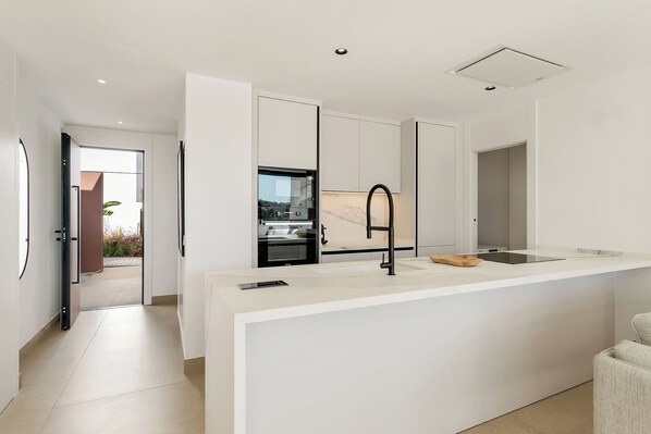 A modern kitchen with white cabinetry, a black faucet, and a built-in oven.