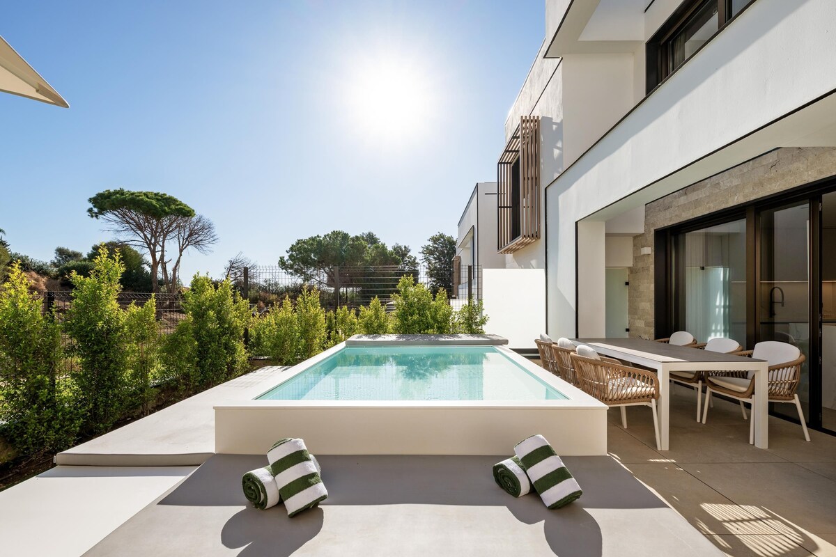 A modern outdoor pool area with a sun lounger and a dining set.
