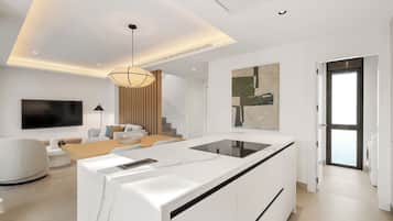 A modern kitchen with a central island, a dining area with a sofa and table, and a staircase leading to an upper level.