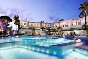 Un resort moderno con un amplio espacio de piscina, numerosas tumbonas y un jardín bien cuidado.