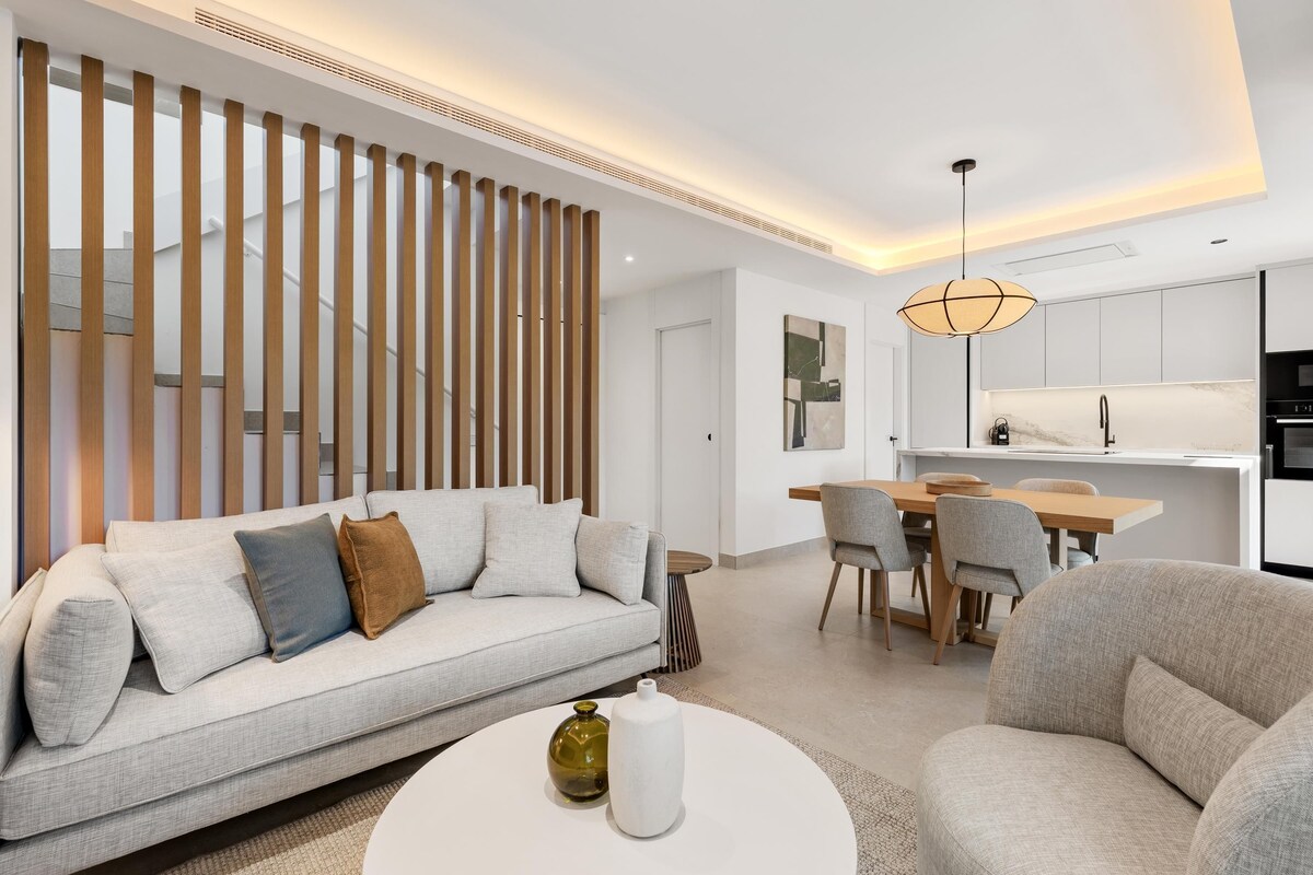 A modern living room with a sofa, a dining table, and chairs.