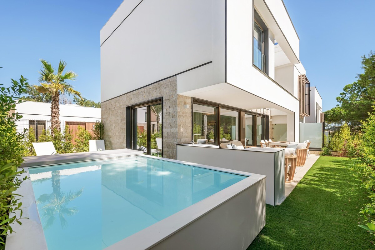 A modern house with a swimming pool, outdoor seating, and a well-maintained lawn.