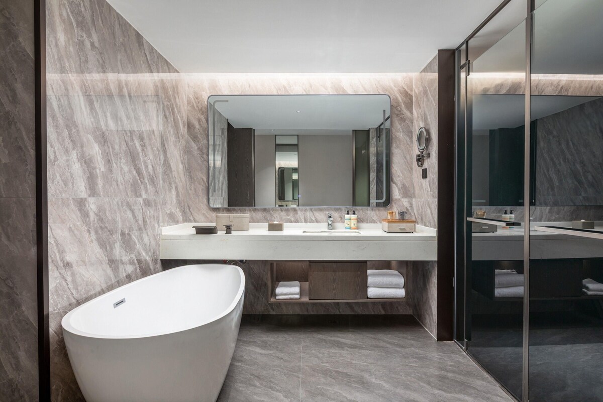 Une salle de bain moderne avec une baignoire sur pieds, un grand miroir et un meuble-lavabo avec un plan de travail.