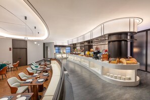 Un espace de restauration moderne dans un hôtel, avec un long comptoir, de nombreux types de sièges et un buffet.