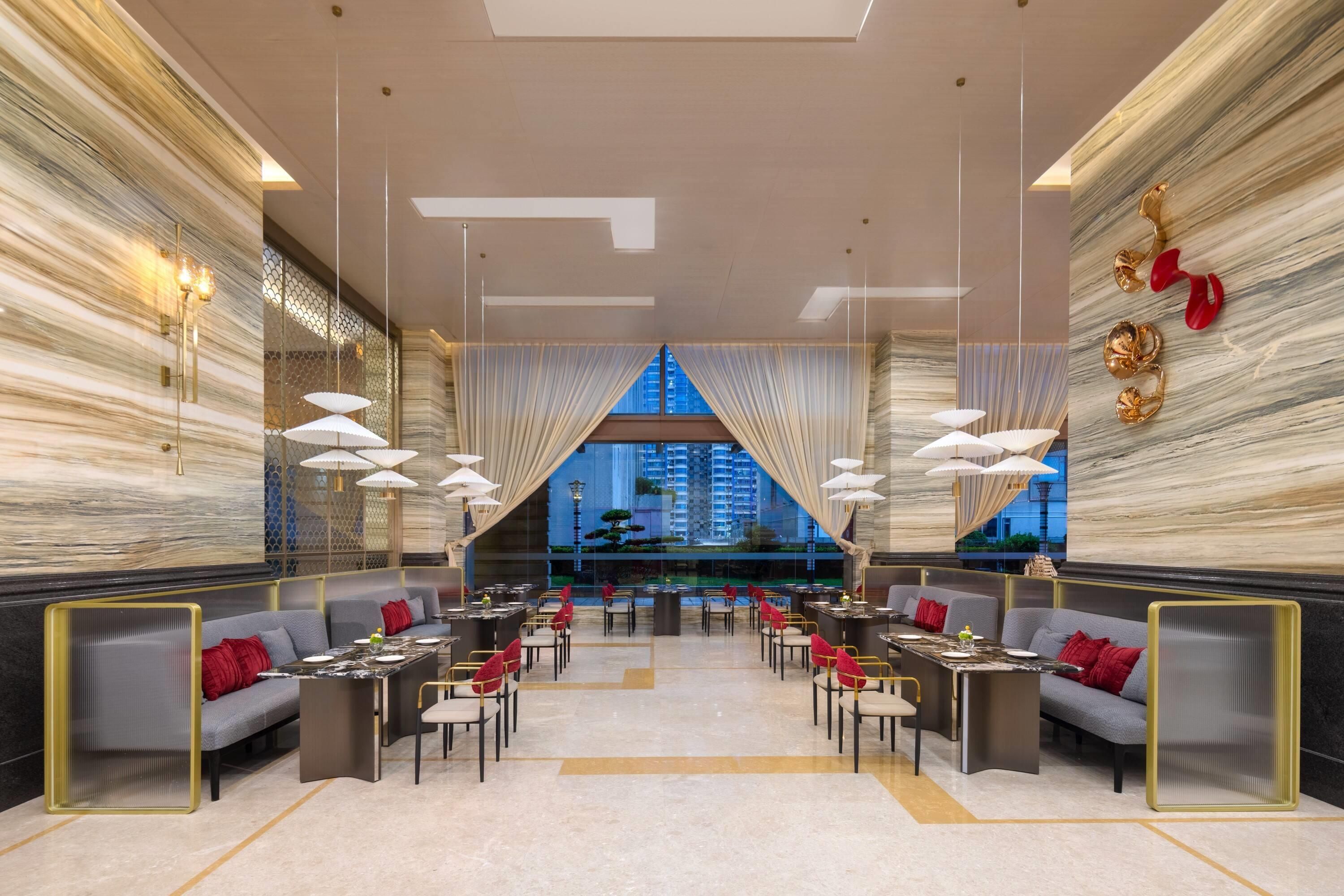 Un interior moderno con una zona de comedor central, distribución de asientos y vistas de la ciudad a través de amplios ventanales.