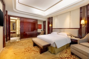 A hotel room with a large bed, a desk, a chair, a wardrobe, and a mirror.