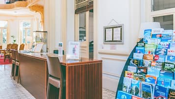 Un espace d’accueil avec un bureau en bois, des chaises et un panneau d’affichage où sont accrochées des brochures de voyage.