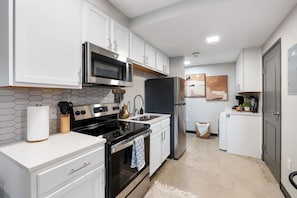 A modern kitchen with white cabinetry, stainless steel appliances, and a tiled backsplash. - Chic Stay in the Heart of 5 Points Free Parking Walk to Food, Fun & Nightlife (Birmingham)