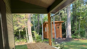 Un tavolo da picnic in legno con panche sotto un portico che si affaccia su una foresta.