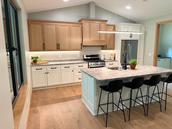 Una cocina moderna con armarios de madera, una isla central con taburetes y un refrigerador integrado.