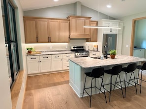 Una cocina moderna con armarios de madera, una isla central con taburetes y un refrigerador integrado.