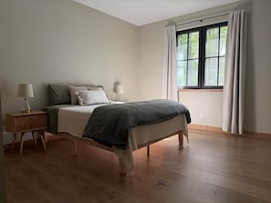 Een slaapkamer met een bed, nachtkastjes en een raam met gordijnen.