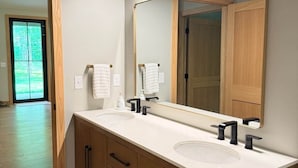 Un bagno moderno con un mobile doppio lavabo, armadietti in legno, uno specchio grande e vista all'esterno.