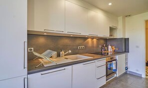 A modern kitchen with white cabinetry, a black countertop, and a built-in oven. - EXCLUSIVE 3-ROOM CANNES APARTMENT WITH MEDITERRANEAN SEA VIEWS (Cannes)