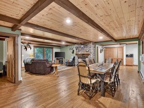 A spacious living area with a wooden dining table, chairs, and a fireplace.