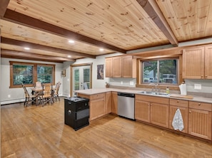 A spacious kitchen with wooden cabinets, a dishwasher, and a dining area with a table and chairs.
