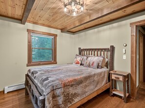 A bedroom with a wooden bed, a nightstand, a window, and a door.