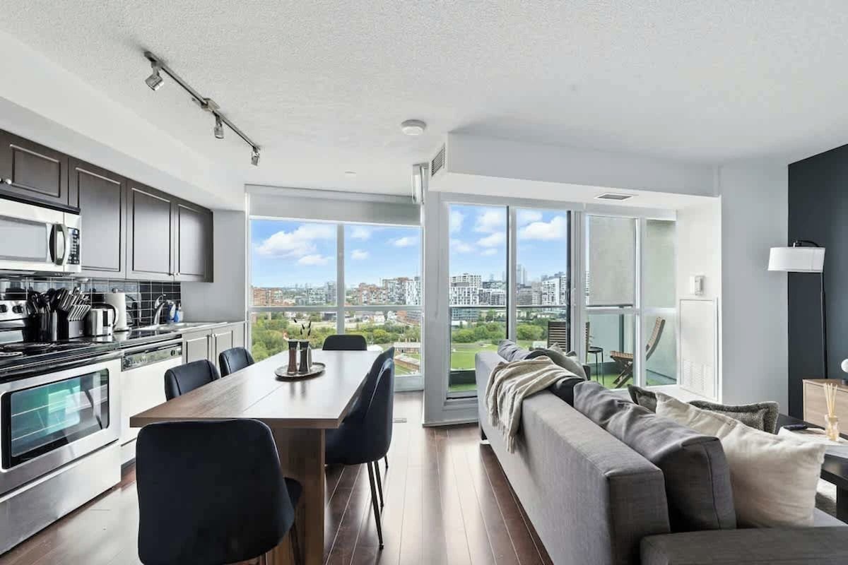 A modern kitchen with a dining area, large windows, and a view of the city.