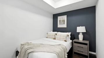 A bedroom with a bed, a nightstand, a lamp, and a framed picture on the wall.