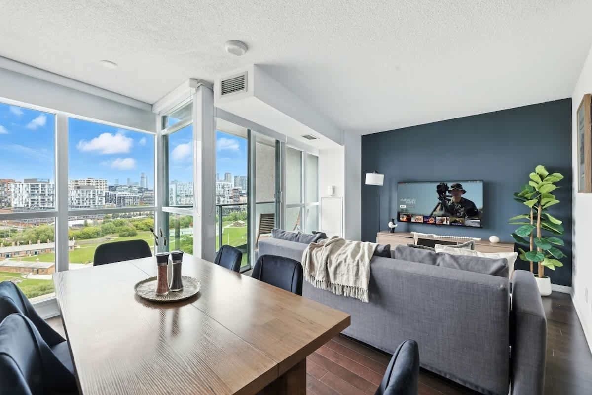 Una sala de estar moderna con comedor, ventanas amplias y vista a la ciudad.