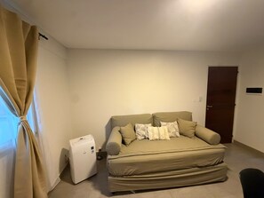 A small, single-room apartment with a bed, a small heater, and a door. - Modern, comfortable apartment in Salta with an excellent location — VRTEAM (Salta)
