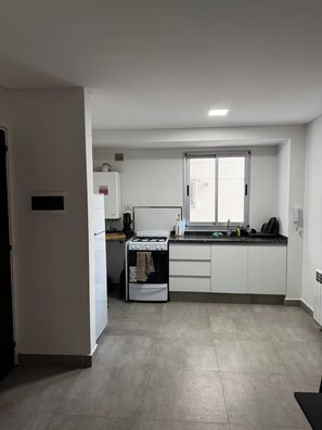 A compact kitchen with a gas stove, a sink, and a window. - Modern, comfortable apartment in Salta with an excellent location — VRTEAM (Salta)