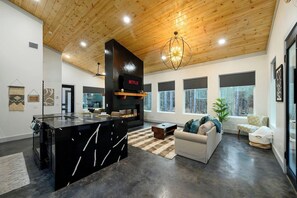 A modern living room with a fireplace, a large island, and a sofa. - Sauna, Hot Tub, Fire Pit, Pets, EV Plug, Secluded (Broken Bow)