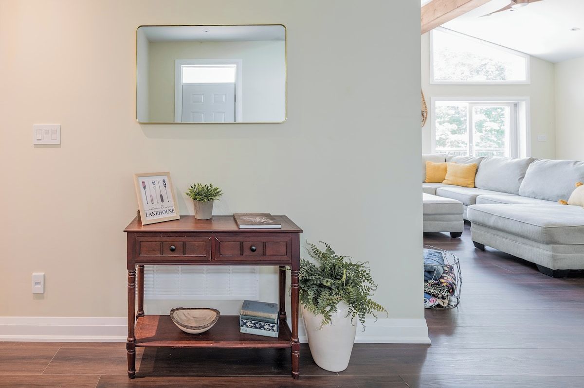 Un salon avec un canapé, une console surmontée d’un miroir et une plante en pot.