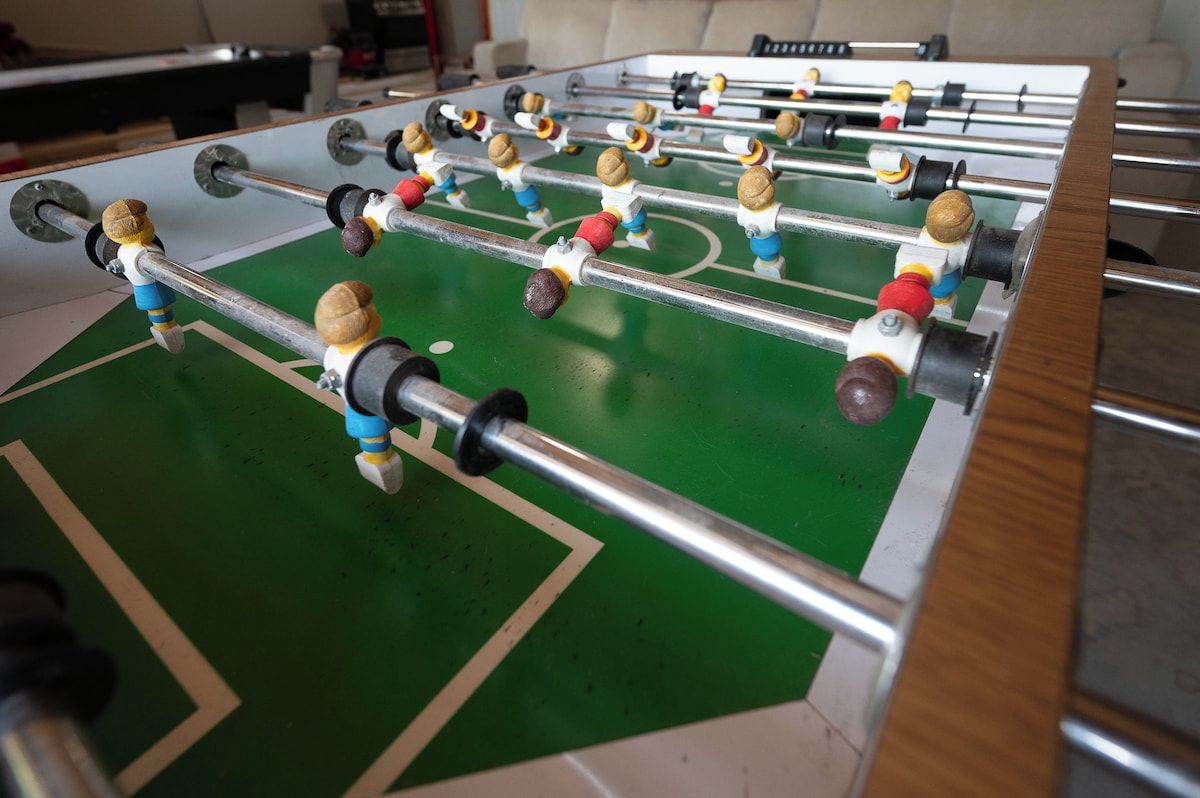 Ett bordfotbollsspel med flera spelare och en grön spelyta.