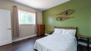 A bedroom with a bed, a dresser, a window with curtains, and two wall-mounted decorative items.